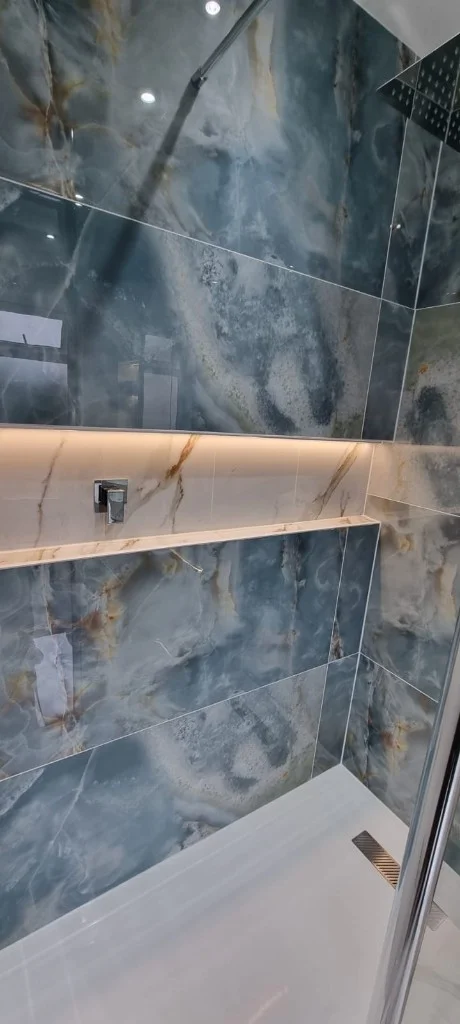 Walk-in shower with marble-effect tiles and chrome rainfall head in Blyth