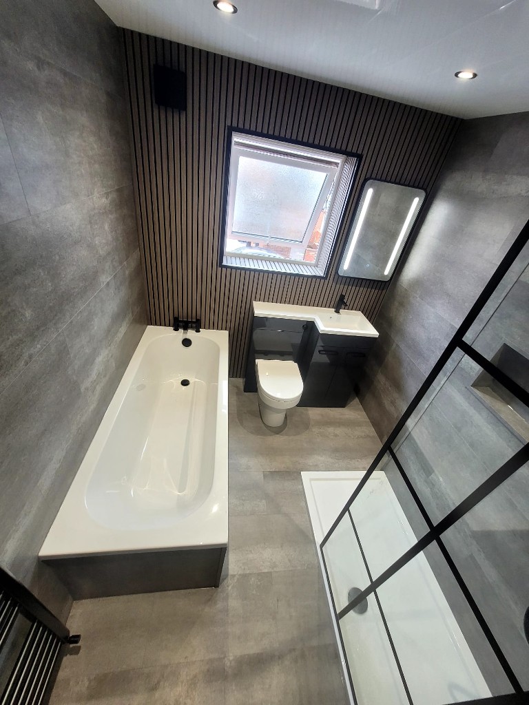 Grey tiled bathroom in Boldon with bath, shower and black towel rail
