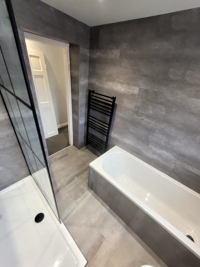 Built-in bath with black taps and heated towel rail in Boldon