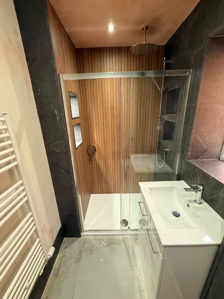 Walk-in shower with wood feature wall and recessed tile shelves in Durham