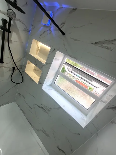 Walk-in shower with LED-lit recessed niches and black rainfall head in Ramsbottom