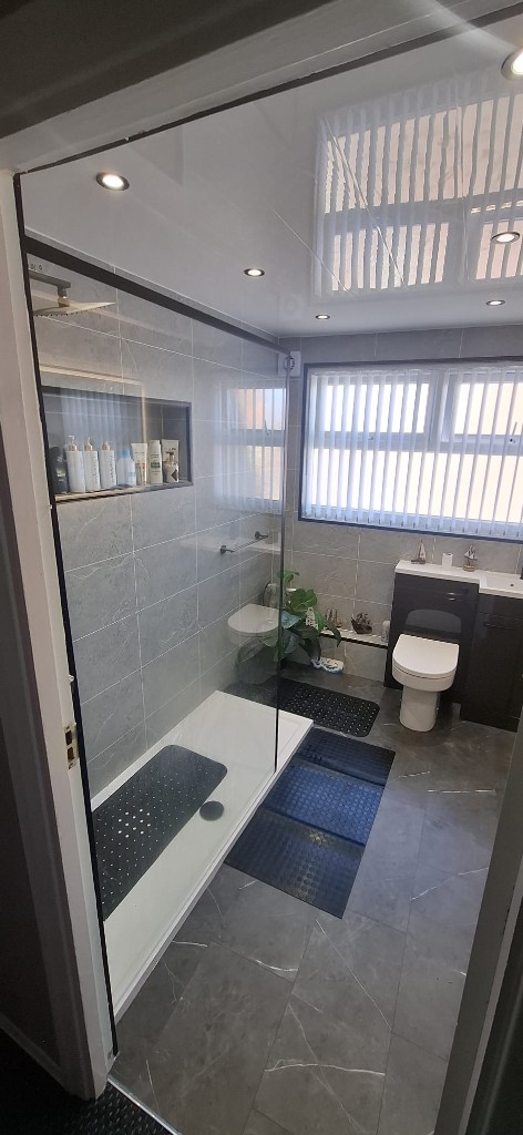 Marble-tiled bathroom in South Shields with walk-in shower and dark vanity unit