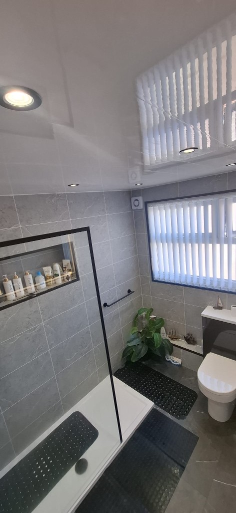 Walk-in shower and back-to-wall toilet in a marble-tiled South Shields bathroom