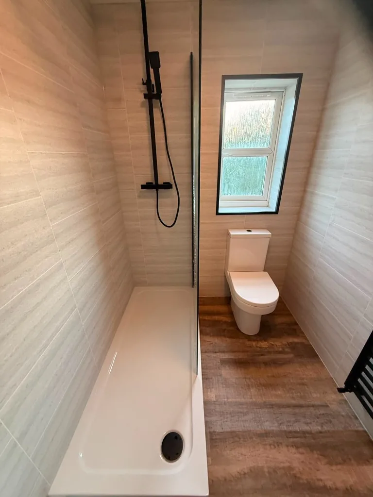 Tile-effect cladded walls, walk-in shower and toilet under frosted window after renovation in Tow Law