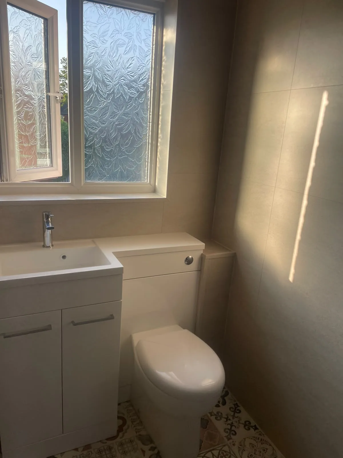 White combination vanity and back-to-wall toilet under frosted window in Wingate