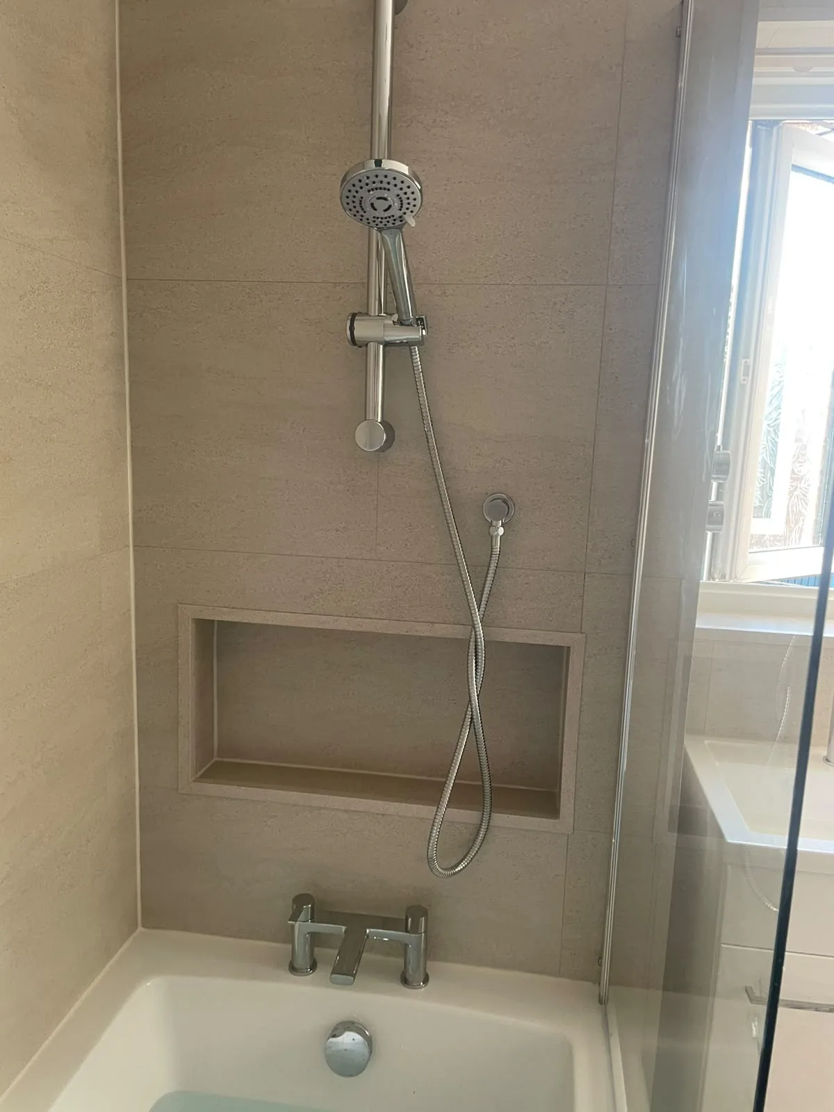 Bath with chrome shower, recessed niche and beige SPC wall tiles in Wingate