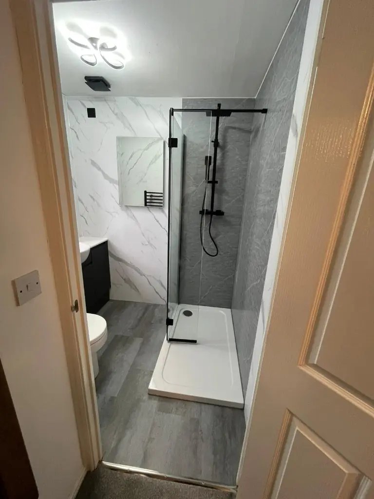 Finished Spennymoor bathroom from the doorway — walk-in shower, dark vanity and white marble cladding