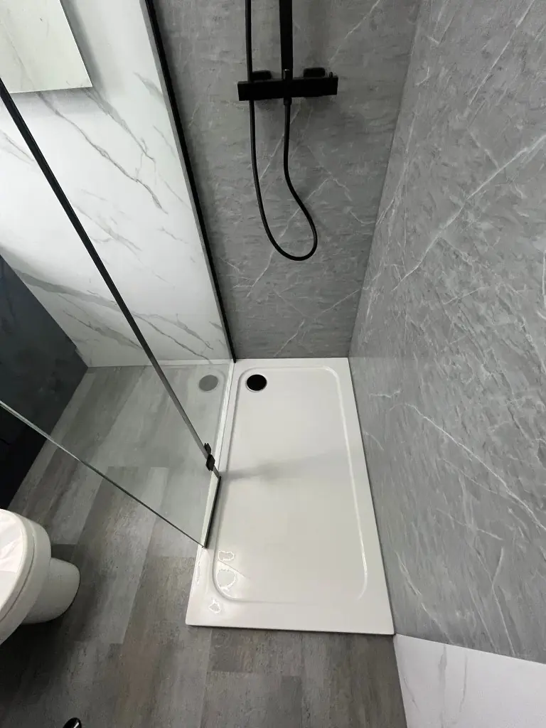 Low-profile shower tray meeting grey SPC flooring beside grey and white wall cladding in Spennymoor
