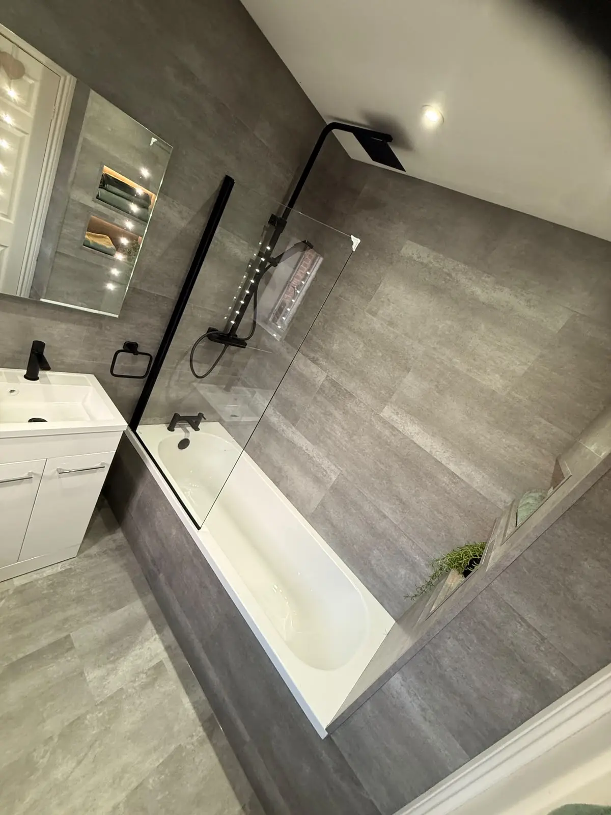 Matte black rainfall shower over bath with LED niches and grey SPC tiling in Chester-le-Street