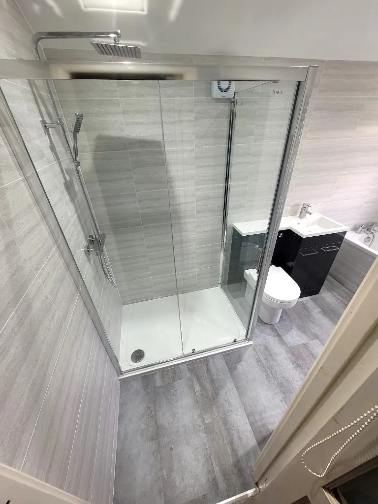 Corner shower quadrant with chrome rainfall head and grey cladded walls in Durham