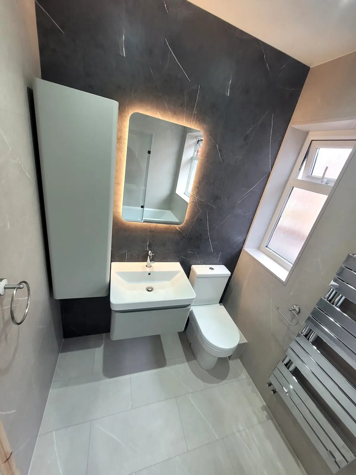 Floating vanity, backlit LED mirror and chrome designer radiator in Sunderland bathroom