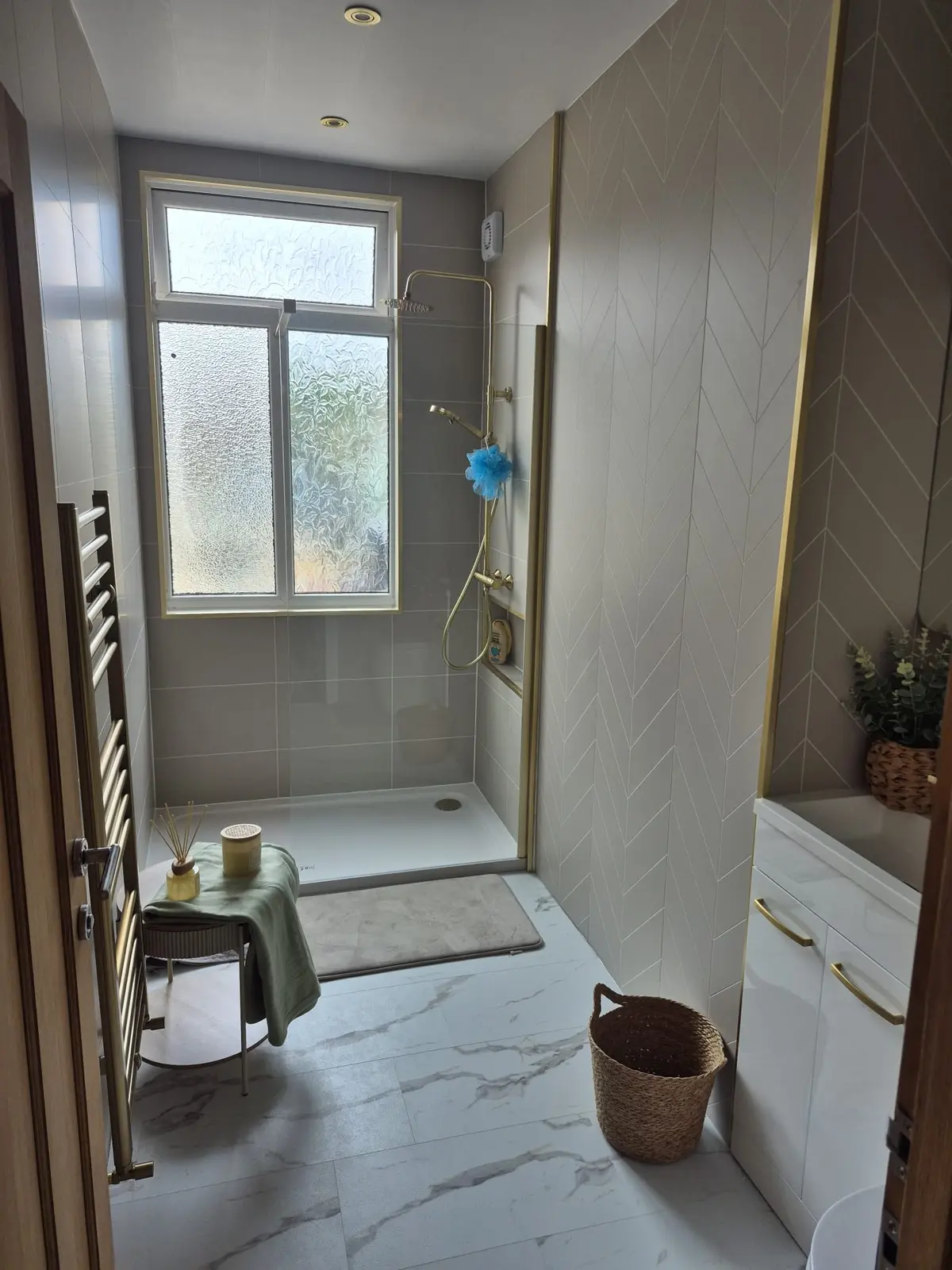 Finished Darlington bathroom from the doorway — walk-in shower, herringbone wall, brass towel rail and white vanity