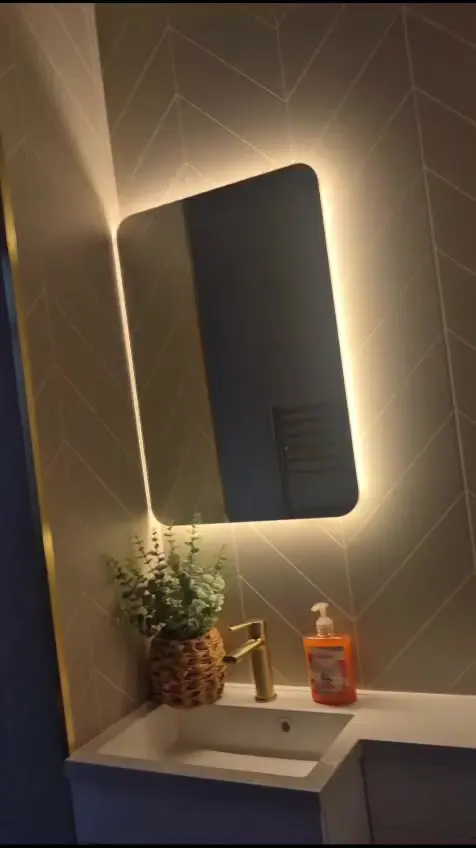 White vanity with brushed brass tap and warm backlit LED mirror on herringbone cladding in Darlington