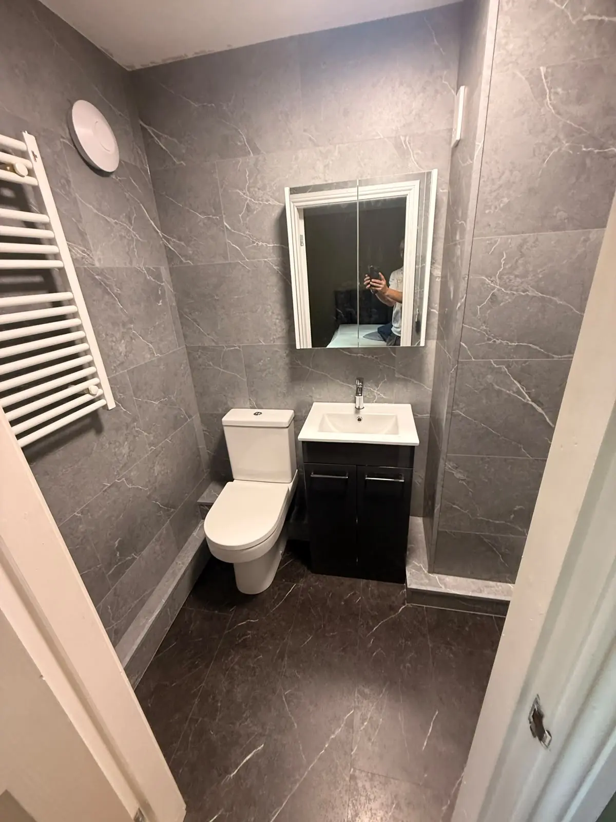Dark vanity unit with mirrored cabinet and heated towel rail in a small Durham bathroom