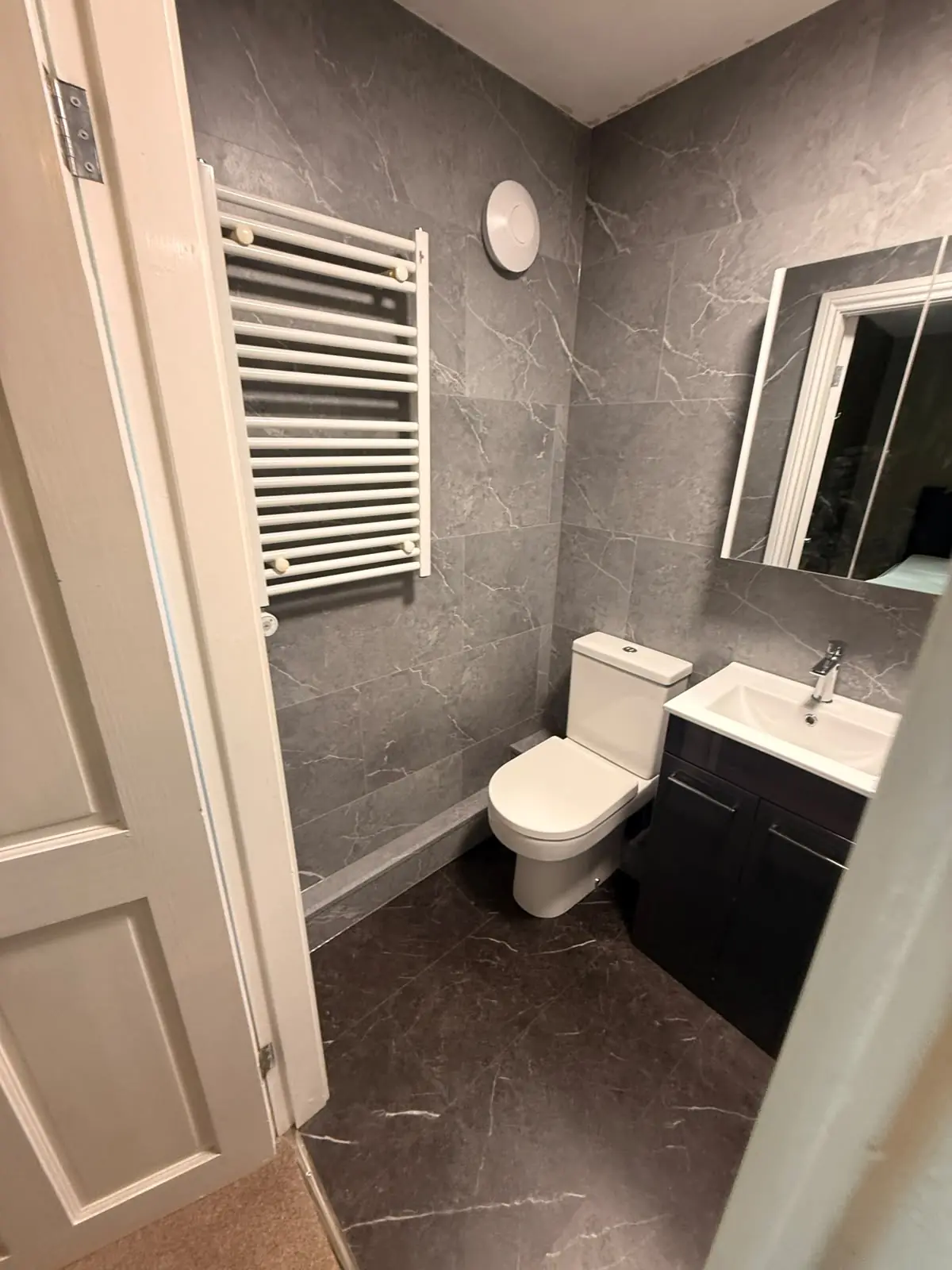 Grey SPC wall panels with toilet, vanity and white heated towel rail in Durham