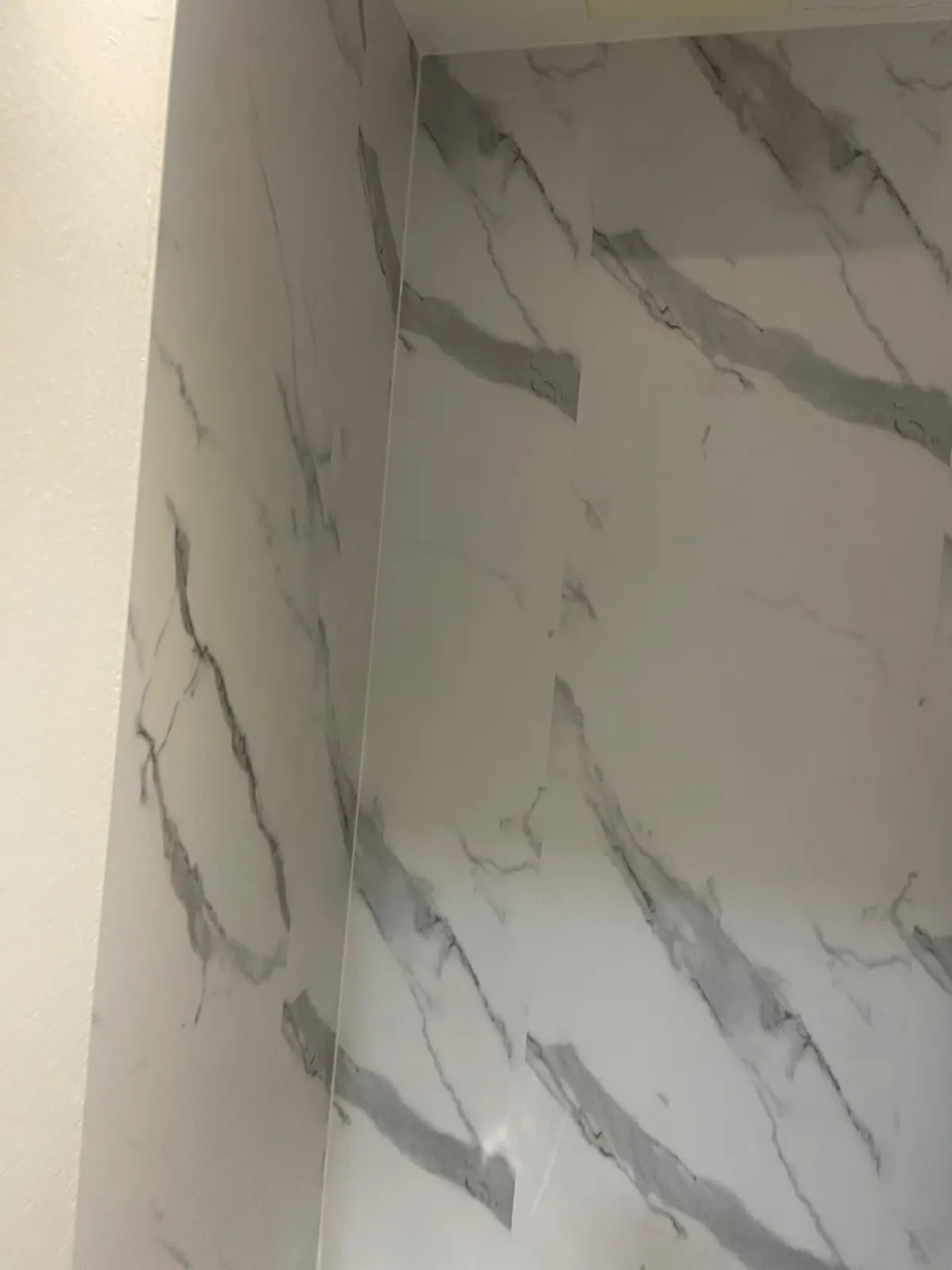 White marble wall cladding and marble-effect flooring in the downstairs cloakroom