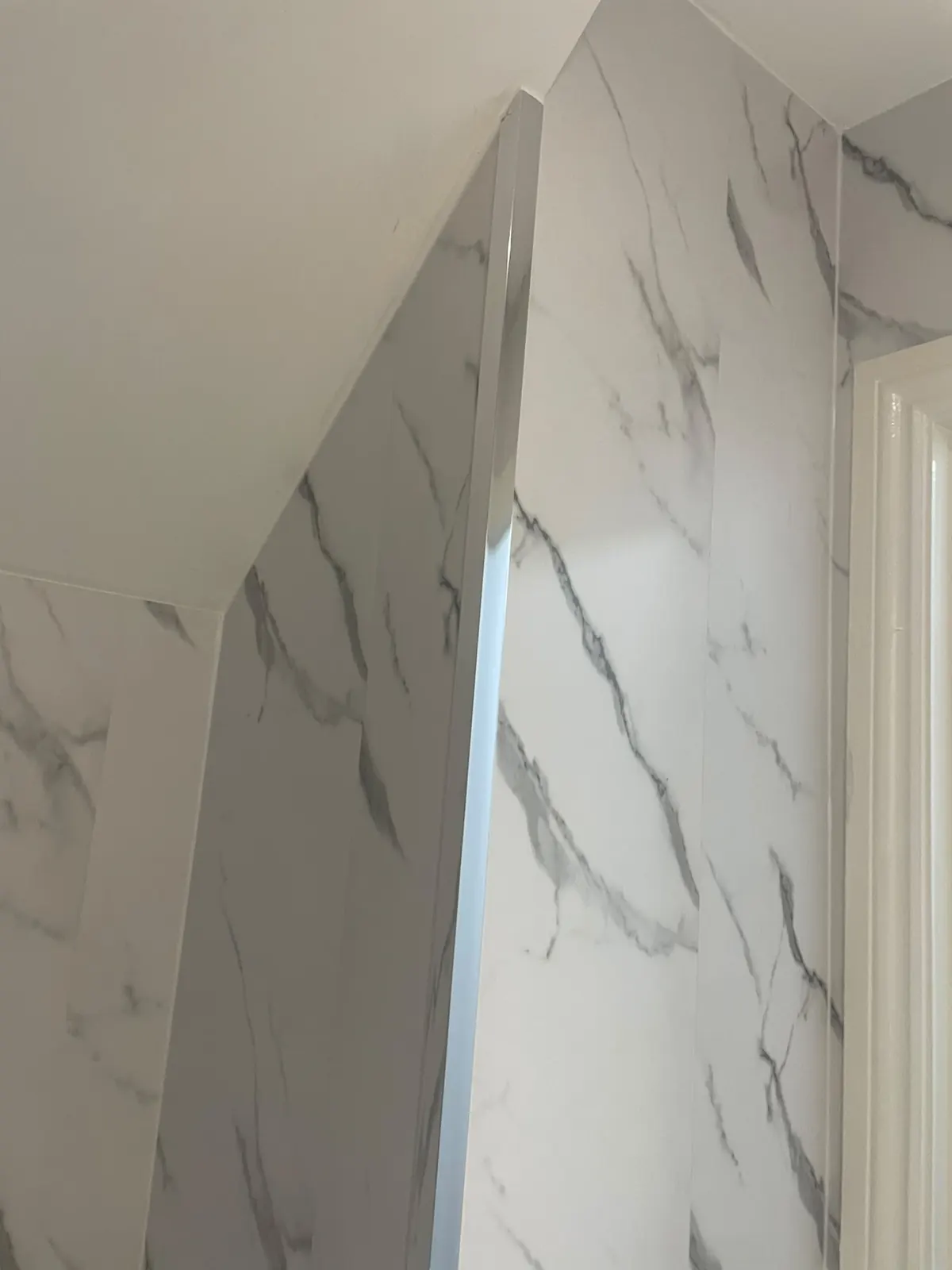 White marble cladding carried up to a sloped ceiling in the downstairs cloakroom