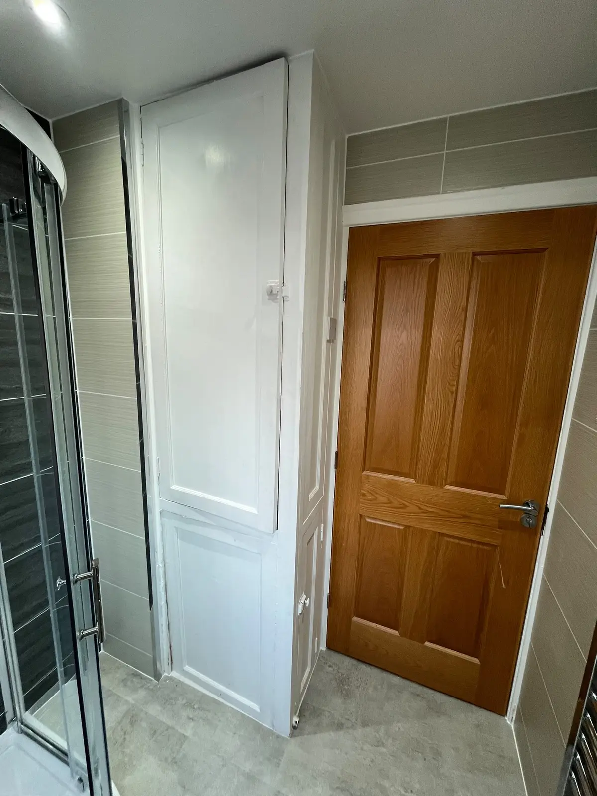 Tall white storage cupboard fitted beside the oak door and shower in Quarrington Hill
