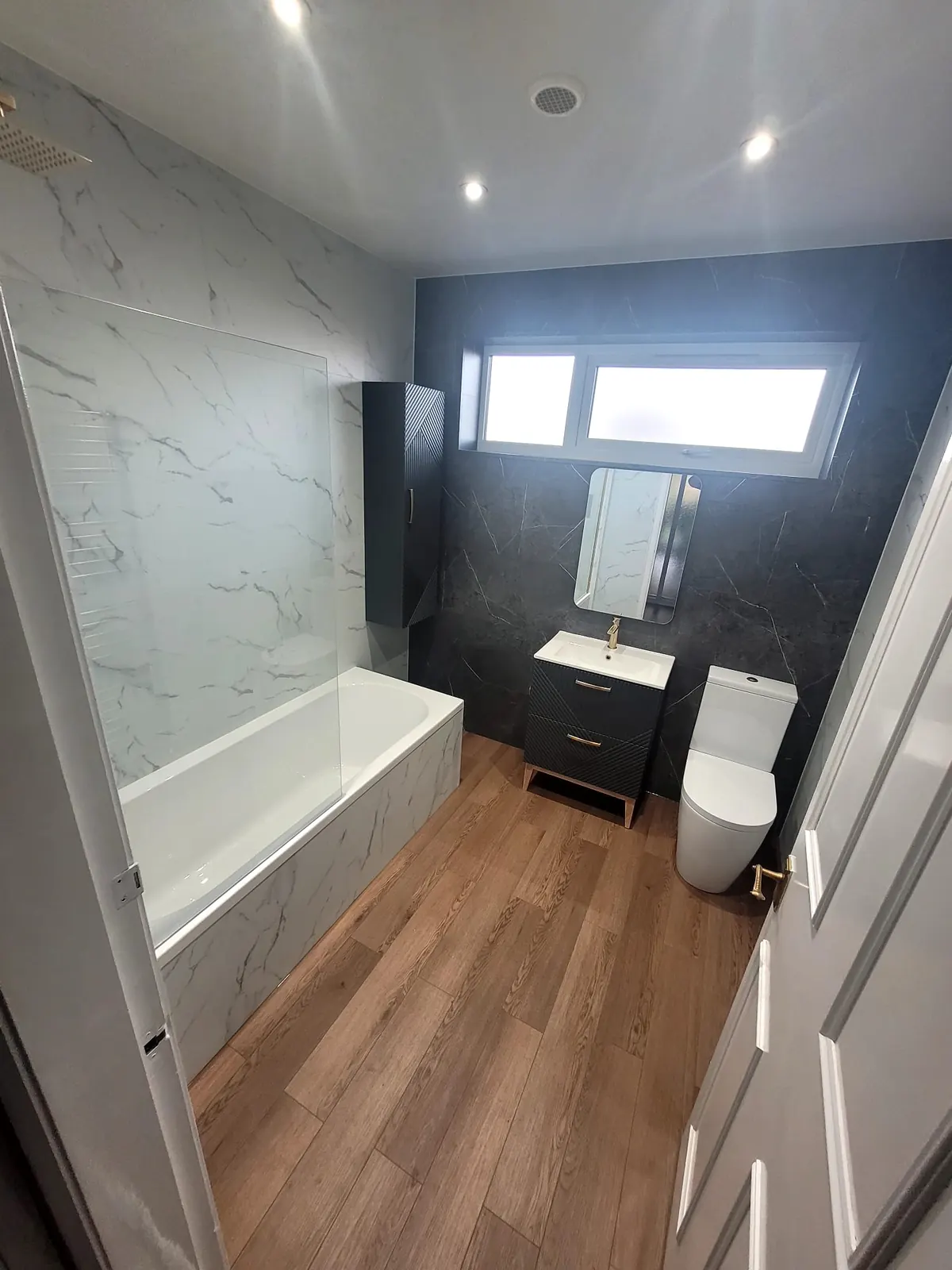 Durham bathroom with white Trevore SPC tiles, Venus Carrara feature wall, floating vanity and waterproof plank flooring