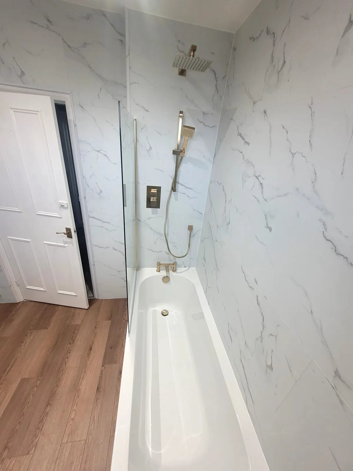 Bath and brass shower fittings with white marble-effect SPC tiles in Durham