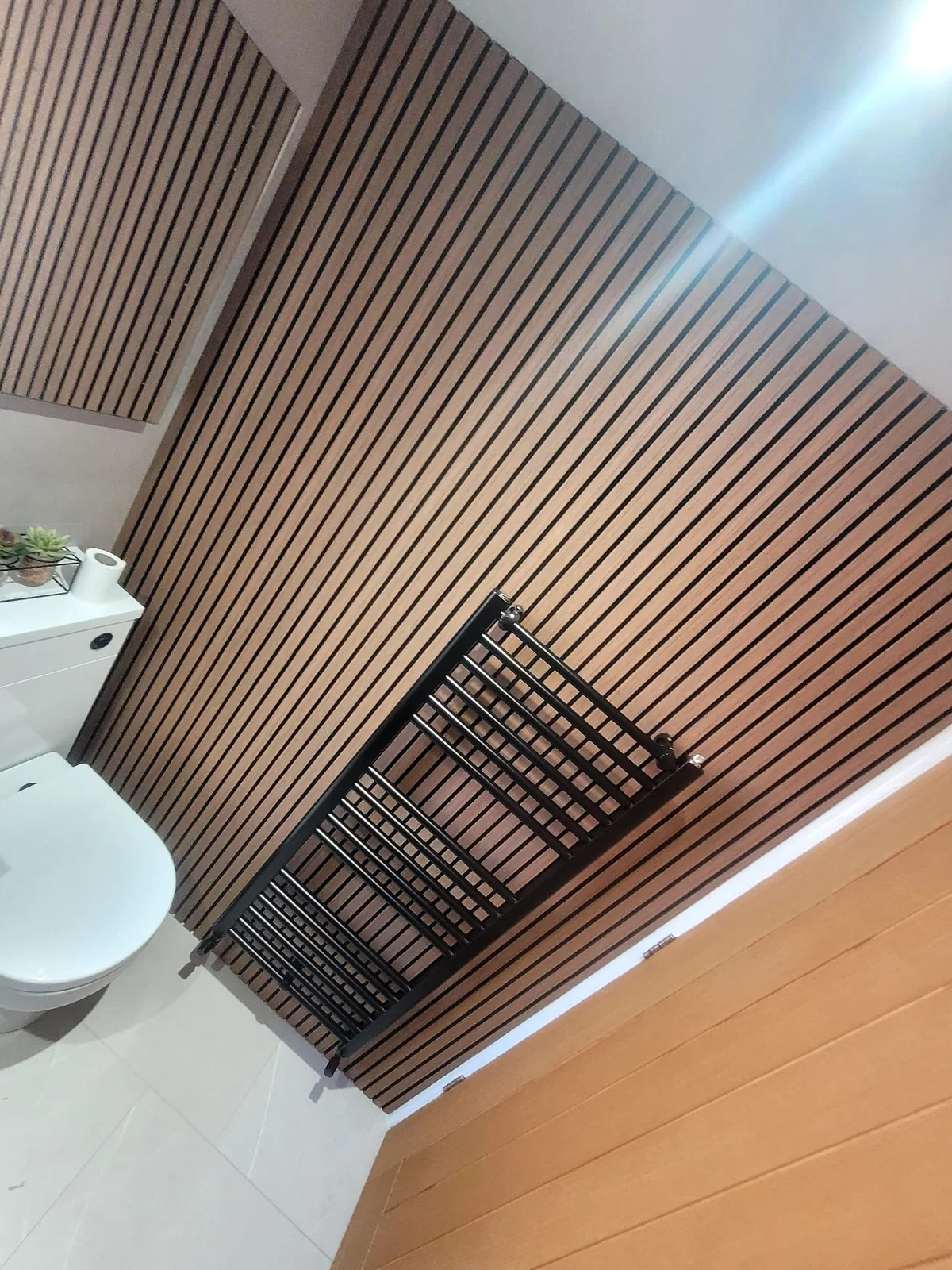 Vertical wood-slat wall with matte black heated towel rail in Sunderland bathroom