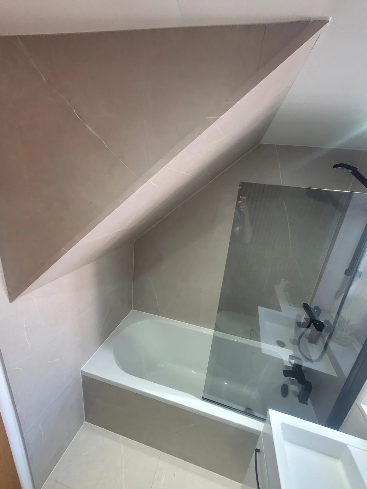 Shower-over-bath with black glass screen under a sloped ceiling in Sunderland