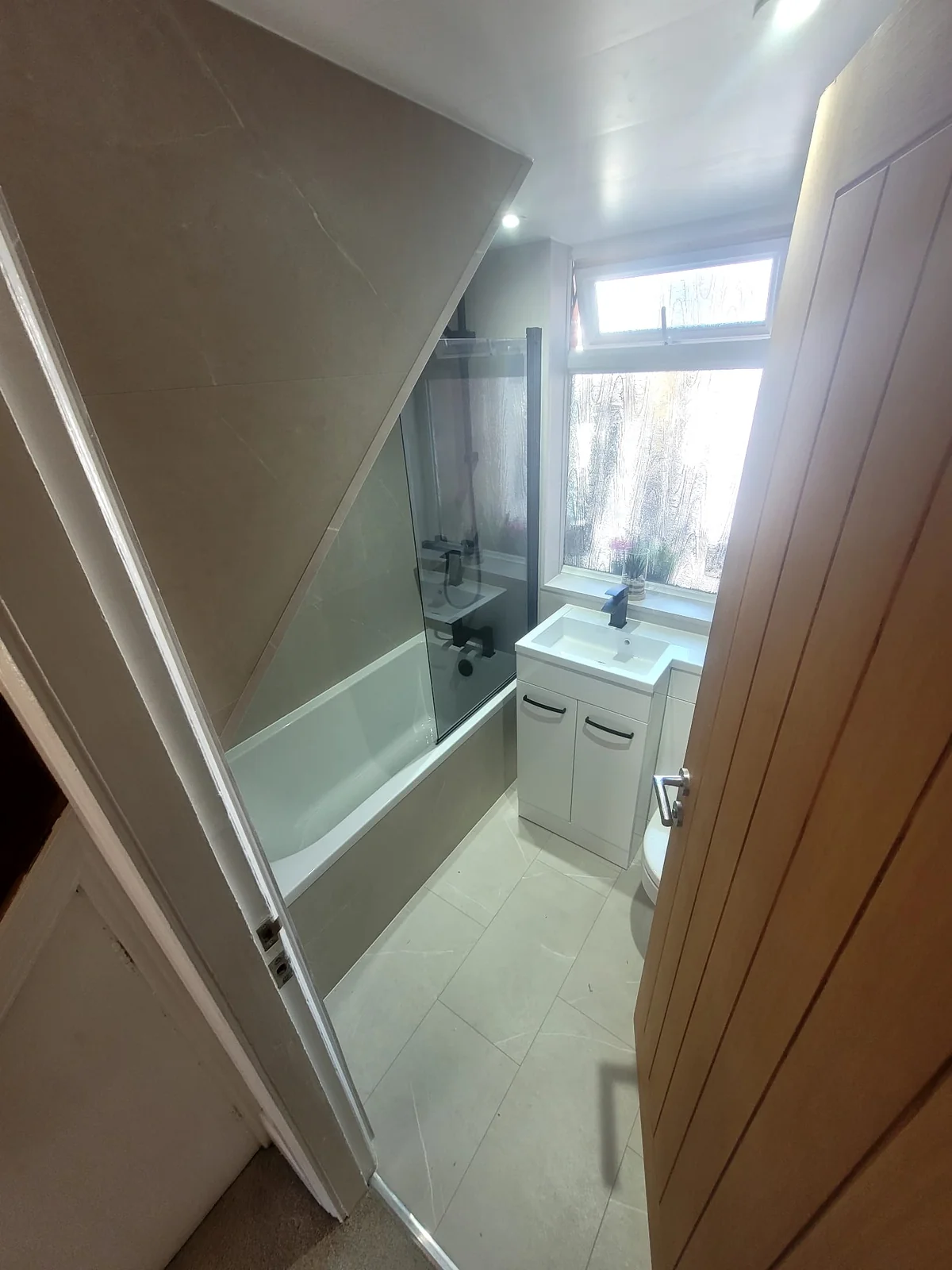 Doorway view of stone-effect tiled bathroom with black fittings in Sunderland
