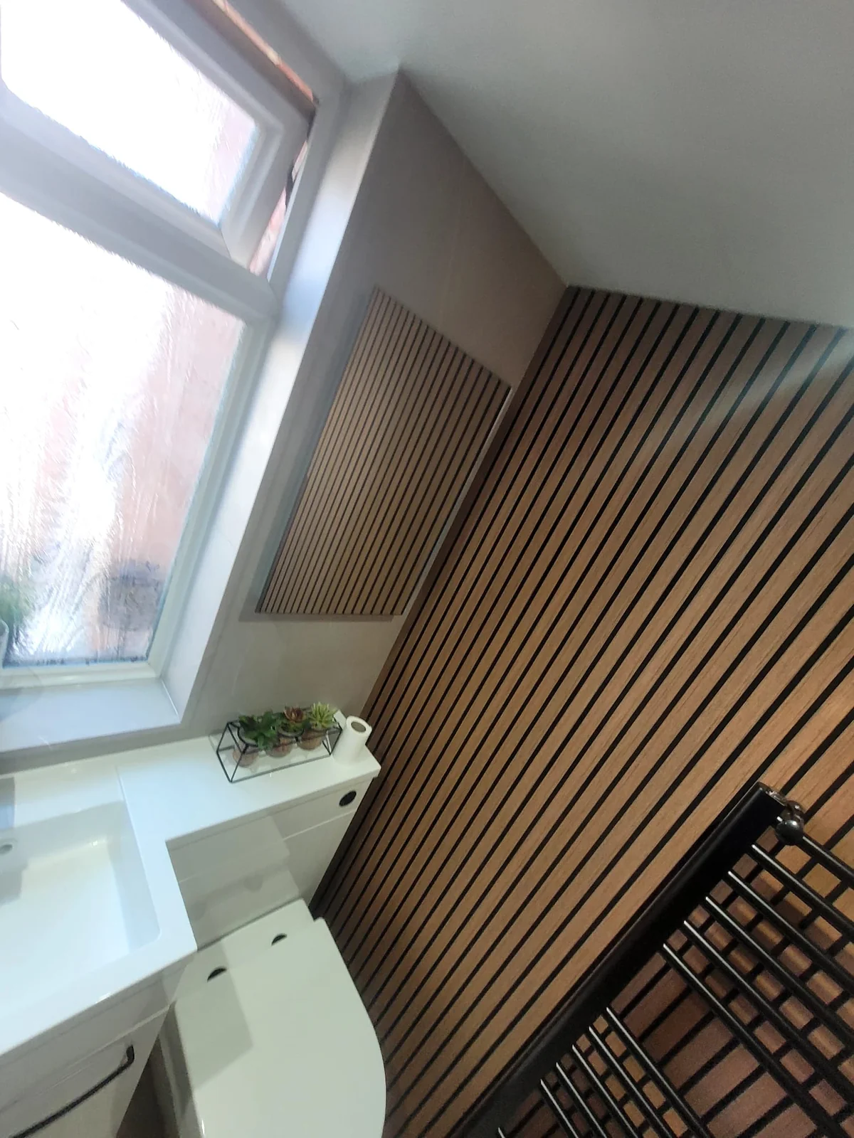 Wood-slat feature wall and frosted window in a Sunderland bathroom installation